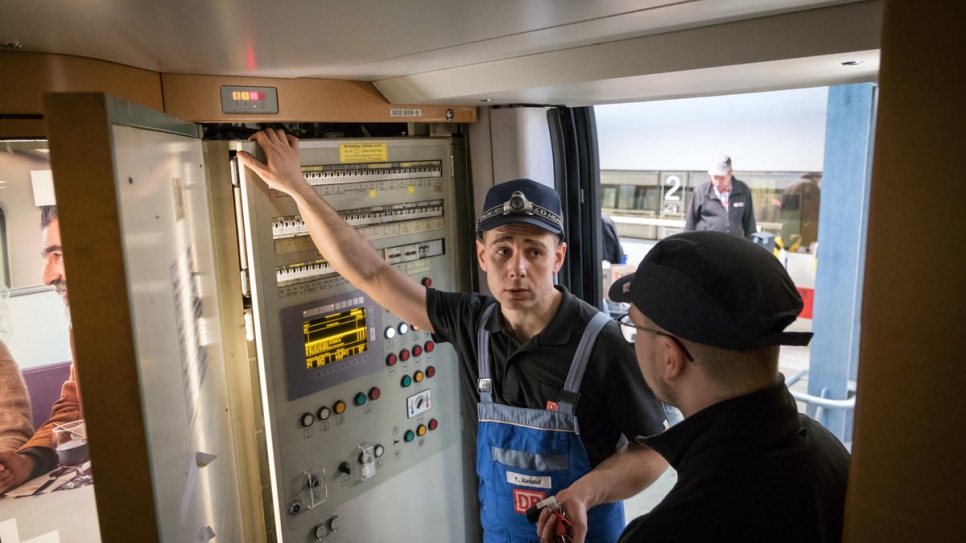 Syrian refugee Mohammad Alkhalaf (left) and his German colleague Dominik Otte, check the electrics of an Intercity Express (ICE) high-speed train, as part of an engineer training programme with Deutsche Bahn.