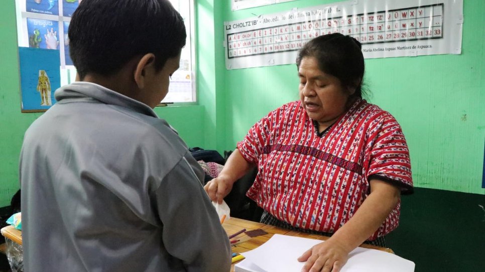 Isai*, un demandeur d'asile nicaraguayen de huit ans (en veste grise) travaillant avec sa professeure de troisième année avant la fermeture de son école, située juste à l'extérieur de Guatemala City. 