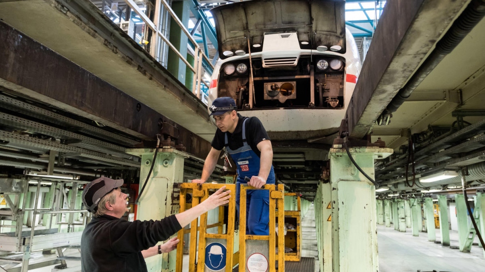 Syrian refugee Mohammad Alkhalaf (right) talks to his trainer Klaus Holzhauer while checking the railcar of an Intercity Express (ICE) high-speed train on an engineering programme with Deutsche Bahn.