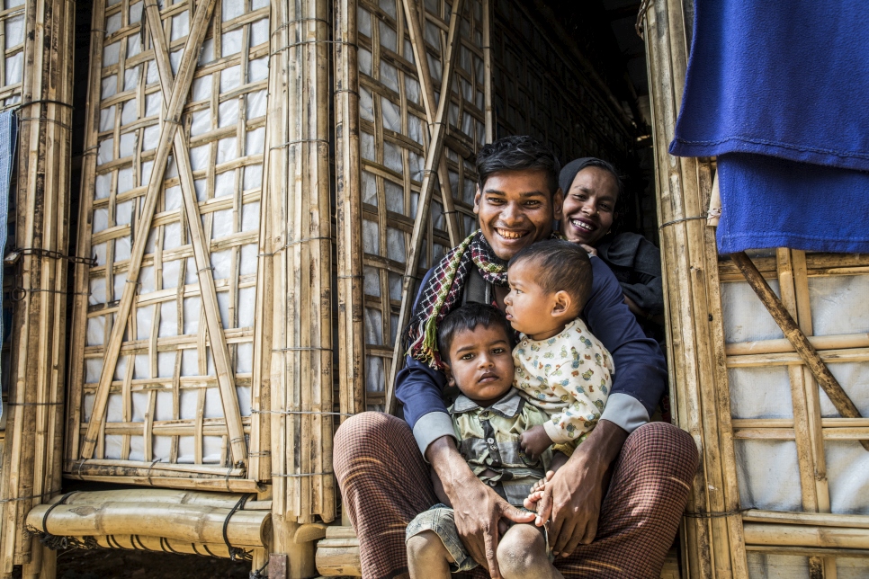 Twenty-seven-year-old Rohingya refugee, Abul Kalam, holds his 17-month-old baby Arafat and three-year-old son Ayaz in the doorway of the new monsoon-ready shelter
