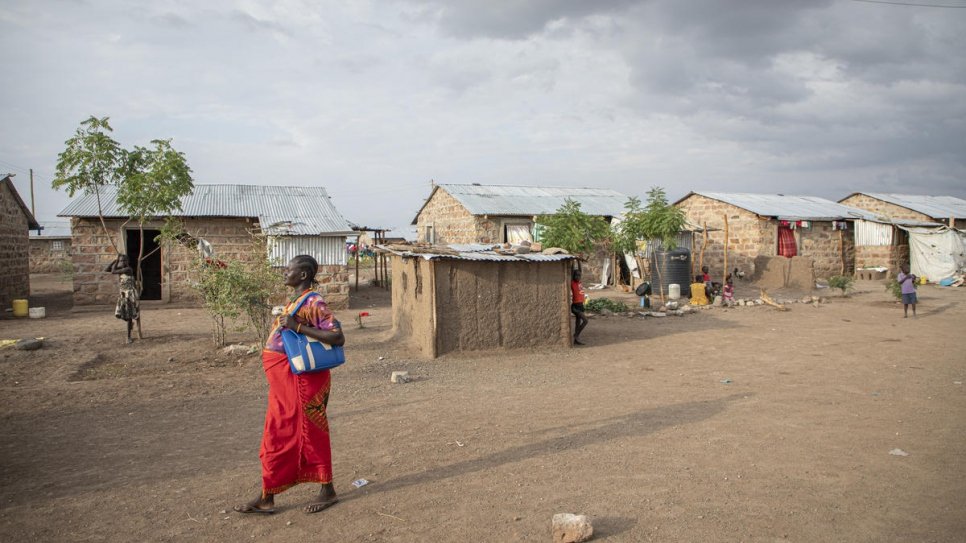 Florence Idiongo walks past newly-constructed homes in Kalobeyei settlement, Kenya. 