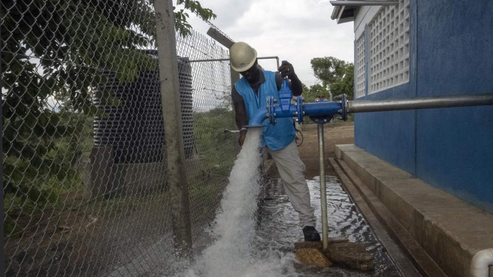 Richard Ochaya, responsable de l'eau, de l'assainissement et de l'hygiène, ouvre l'approvisionnement en eau du projet Obomiri qui permet de distribuer de l'eau à l'installation de réfugiés de Bidibidi grâce à un système de puits et de pompes solaires. 