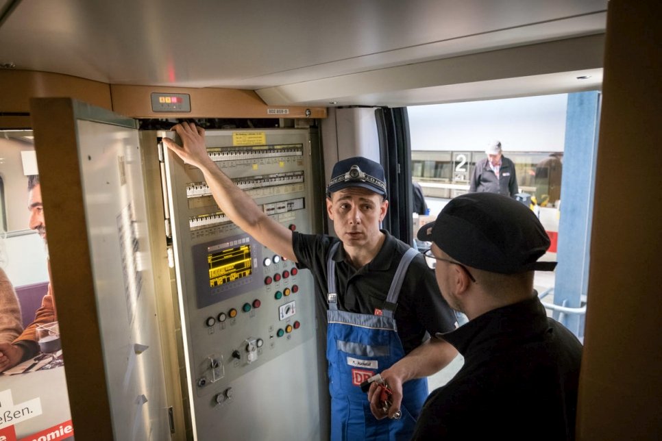 محمد الخلف (يسار) وزميله الألماني دومينيك أوتي، يفحصان كهرباء أحد القطارات عالية السرعة بين المدن، كجزء من برنامج تدريب المهندسين مع شركة "دويتشه بان". 