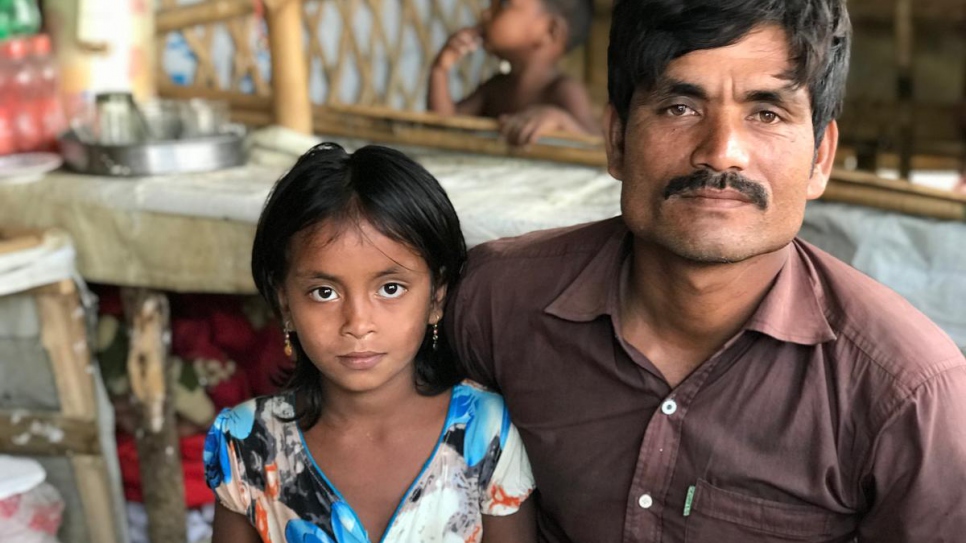 Nurul Salam, 35, sits with his eight-year-old daughter, Janatara, in the tea shop he runs in Kutupalong refugee settlement, Bangladesh.