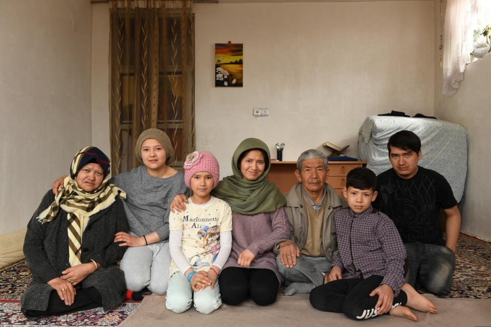 العائدة الأفغانية كوبرا يوسفي (في الوسط) البالغة من العمر 27 عاماً، تجلس مع والديها وإخوتها (من اليسار) سايرا يوسفي ومريم وحورة ومحمد ومهدي ومحمد علي.
