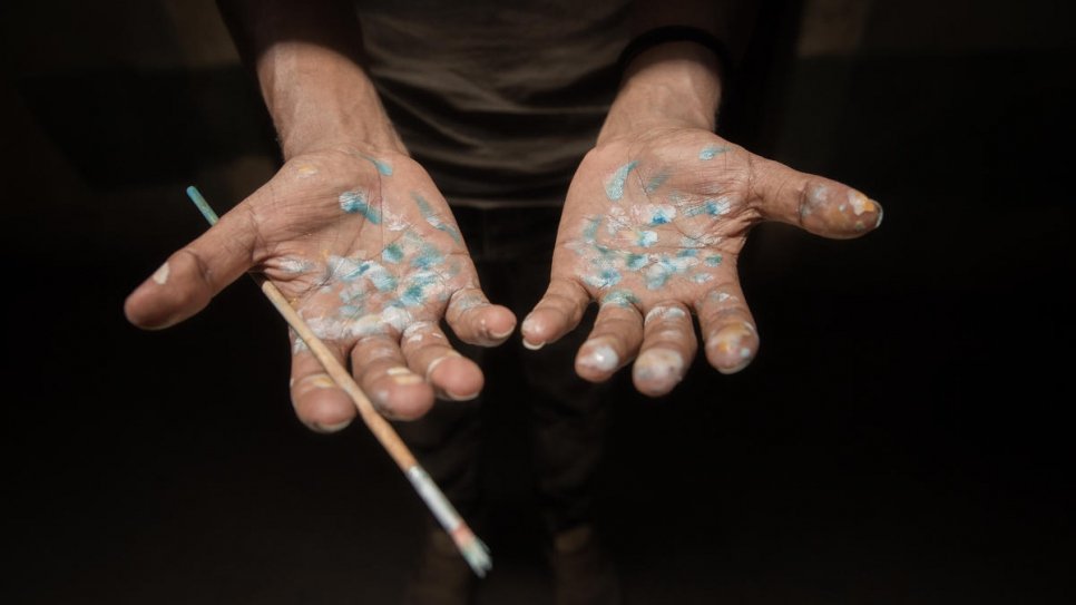 Solomon displays his paint-spattered hands after working in the art room that he shares with other residents.