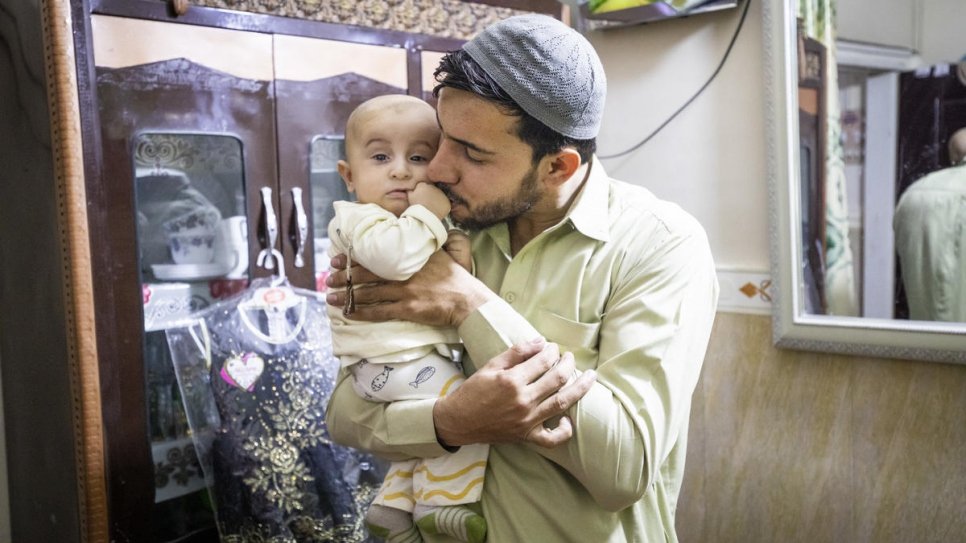 Sifat cradles his son in the small apartment where he lives with his family. 