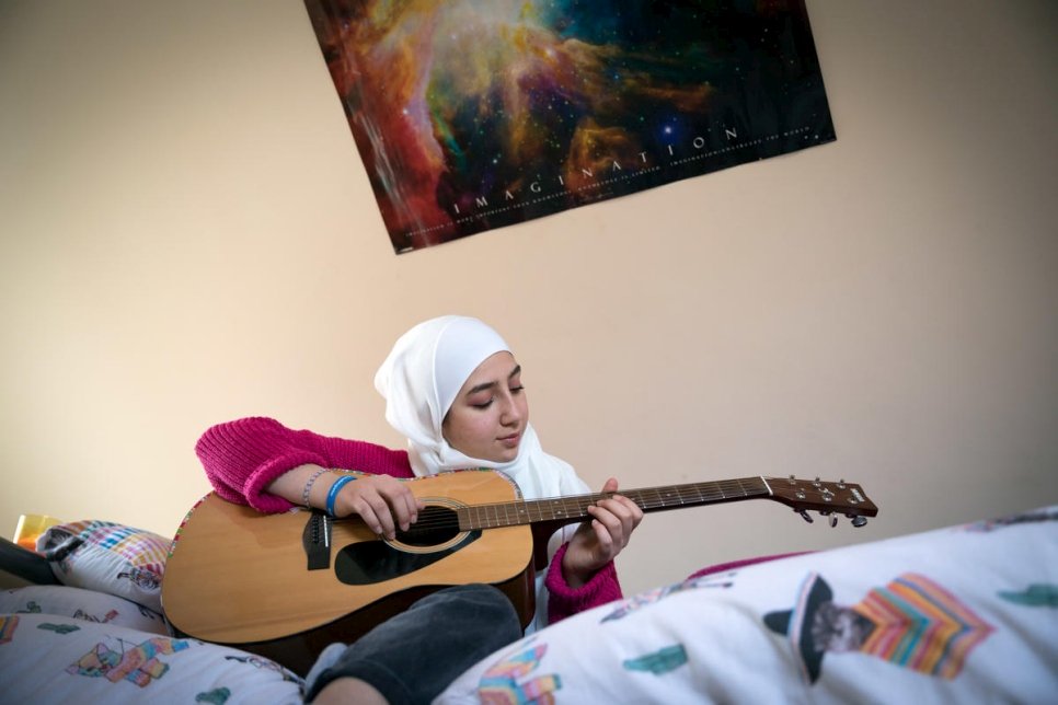 مايا غزال تعزف على الجيتار في غرفة داخل منزلها. 