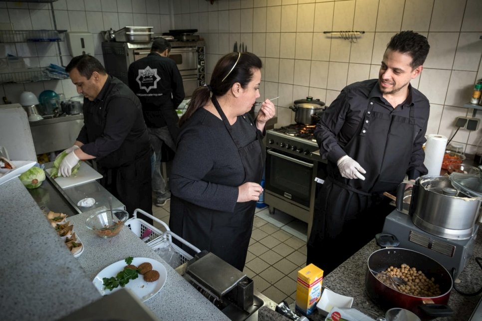 اللاجئة السورية سلمى العرمشي (وسط)، تحضر الطعام مع ابنها فادي الزعيم (يمين) واثنين من الموظفين في مطبخ شركة "ياسمين للضيافة" الواقع في برلين. 