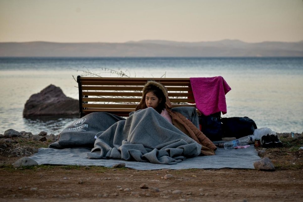 Une jeune fille s'abrite sous une couverture sur la plage de Lesbos en Grèce, le 2 mars 2020. Elle venait de traverser la mer Égée depuis la Turquie à bord d'un canot pneumatique. 