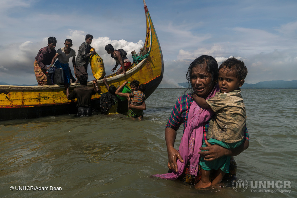 En mor bærer på sit barn, mens hun vader mod stranden ved Dakhinpara, Bangladesh. © UNHCR/Adam Dean