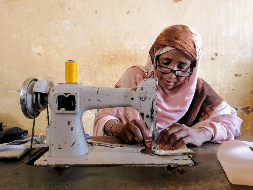 تستخدم فطومة، وهي لاجئة من مالي، ماكينة خياطة لصناعة أقنعة الوجه في ورشة عمل في نيامي.