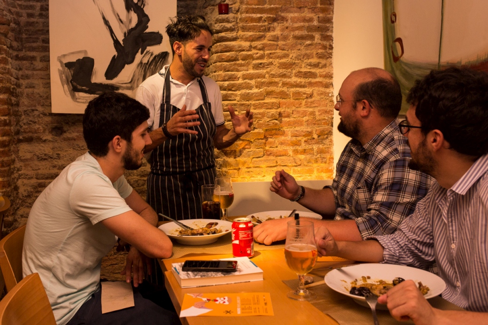 الطاهي اللاجئ محمد يحيى يرحب بالزبائن في مطعم "لارتيزان" في مدريد.