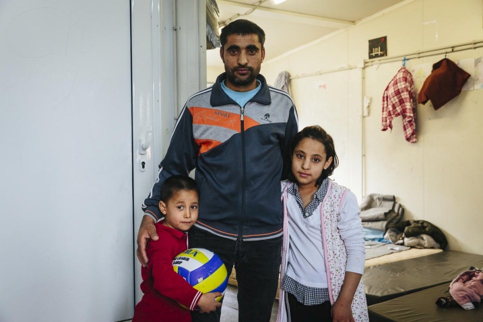 An Afghan asylum-seeker stands with two of his children at a reception centre in Fylakio, Greece, in February 2020.