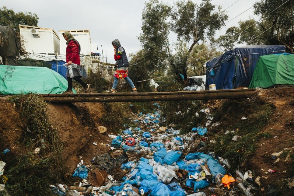 Une demandeuse d'asile afghane et sa fille traversent un fossé rempli de déchets dans une installation spontanée sur l'île grecque de Lesbos. Photo d'archives, novembre 2019.