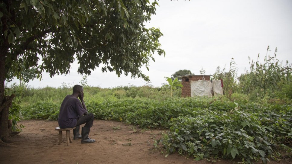 Réfugié sud-soudanais et père de cinq enfants, Adam* est assis devant l'abri qu'il occupe au  site de réfugiés de Bidibidi, en Ouganda. Sa femme Mary* a été diagnostiquée bipolaire 	en 2012 et s'est plus tard suicidée en exil. 