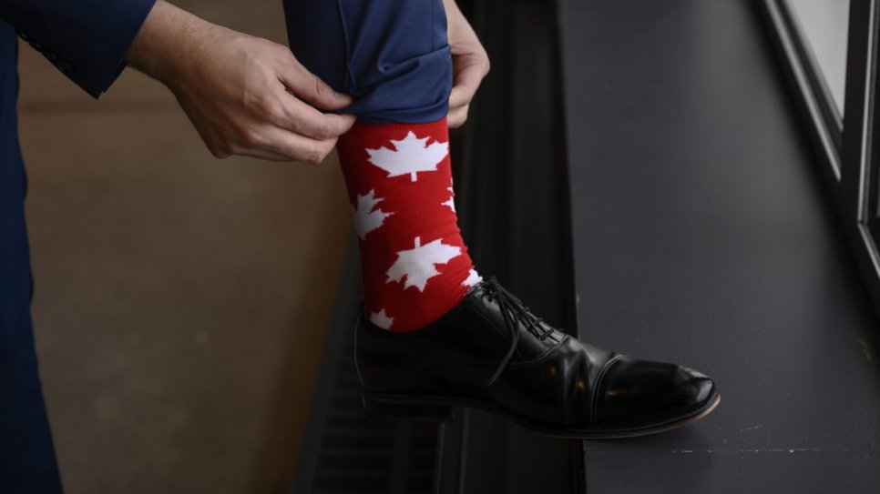 Tareq Hadhad ajuste ses chaussettes aux motifs de feuilles d'érable pendant la cérémonie d'octroi de la citoyenneté canadienne. 