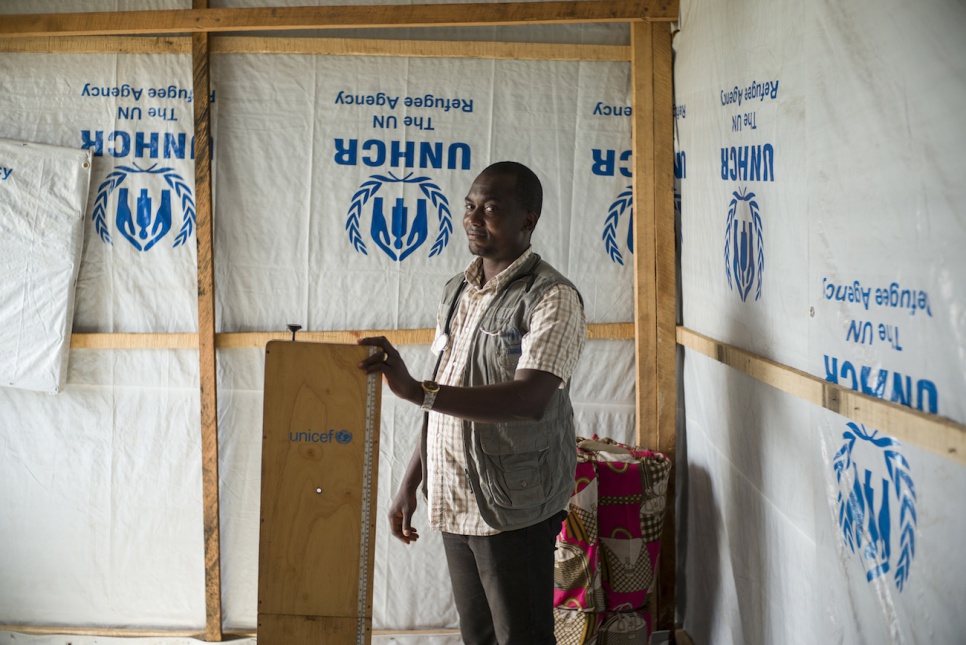 At the mobile health clinic in Congo's Bili camp, Dr. Tony Mayawula holds a scale for weighing refugees and helping to assess their condition.