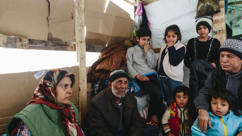Sardar (à droite) dans son petit abri en bois à Lesbos, aux côtés de ses enfants, sa belle-mère et son beau-père aveugle qui a dû être porté durant le périple jusqu'en Grèce. 