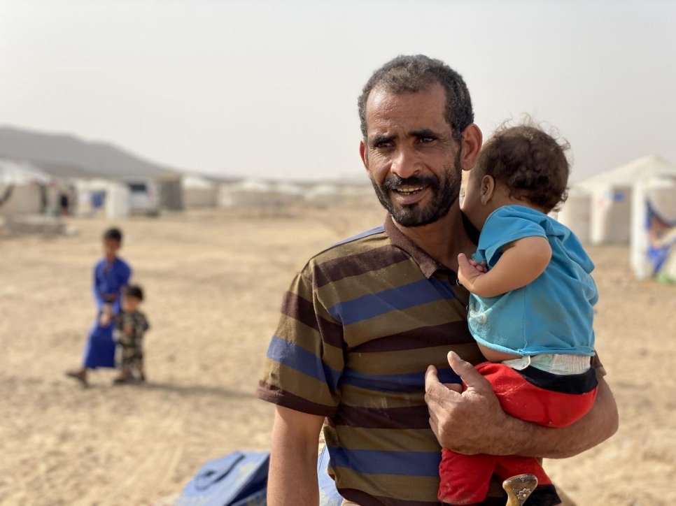 Taher, un Yéménite de 40 ans et déplacé par le conflit, tient dans les bras son plus jeune fils Mustafa, 2 ans, devant leur abri dans le site d'accueil des personnes déplacées au camp de Marib. 