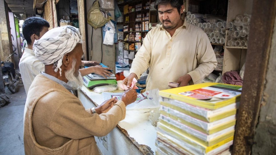Azeem, 27 ans, dans son magasin à Karachi, au Pakistan. Les réfugiés afghans comme Azeem ont récemment été autorisés à ouvrir des comptes bancaires.