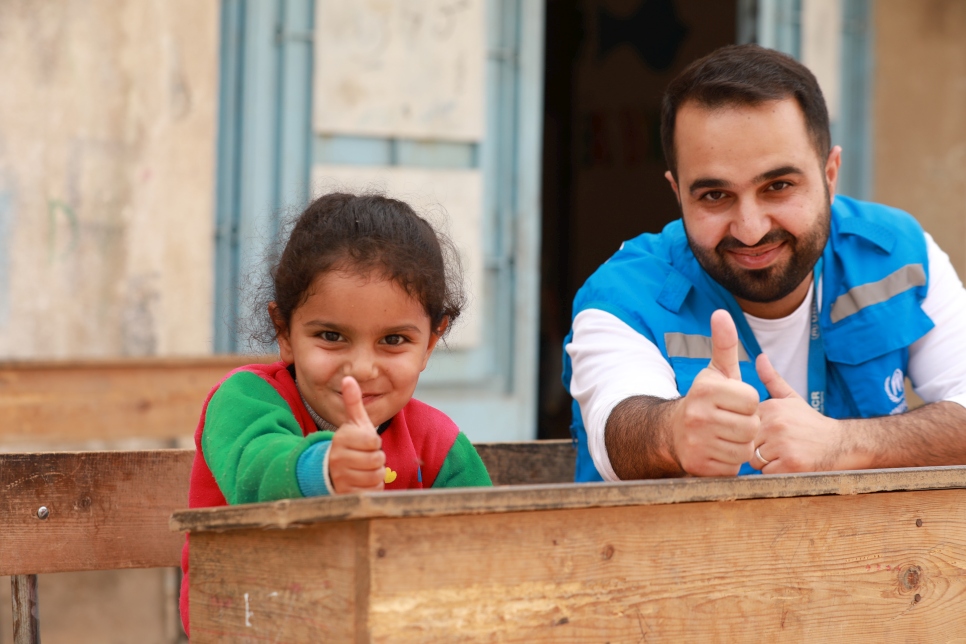 أحمد شمو من فريق المفوضية مع طفلة نازحة في أحد المآوي الجماعية.