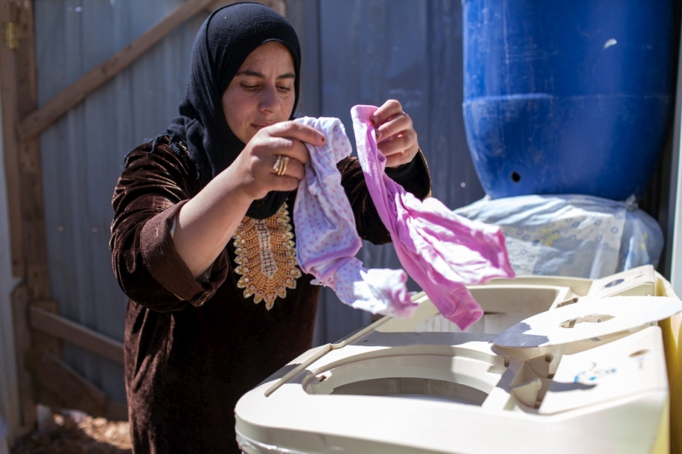 اللاجئة السورية أسمهان تستعمل غسالتها الجديدة لغسل ملابس أطفالها في مخيم الأزرق الذي زود بالطاقة الكهربائية في 17 مايو.