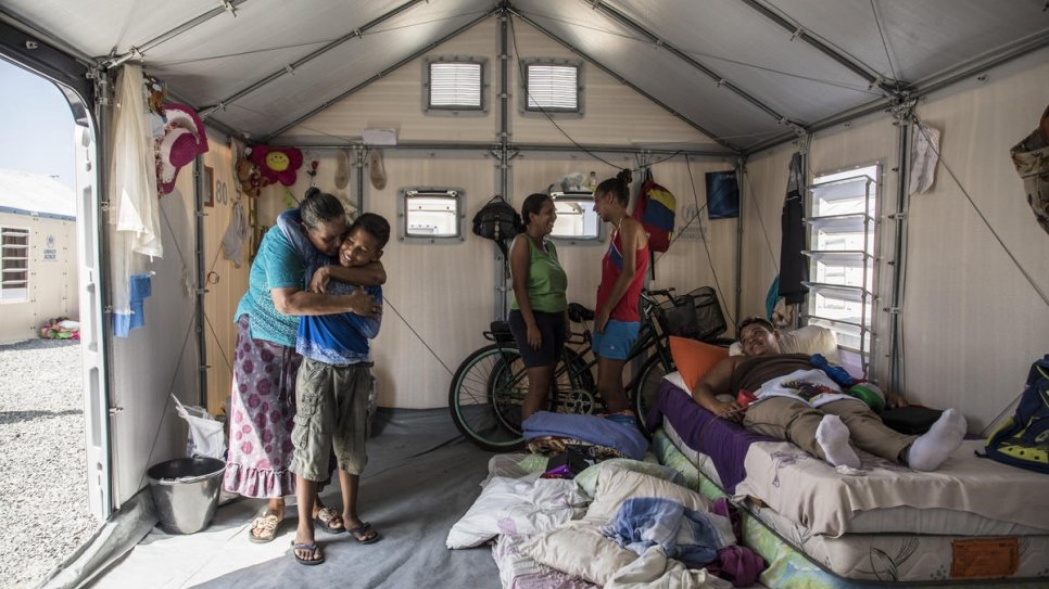 Nelly embrasse son petit-fils Moises dans la tente familiale à Boa Vista, Brésil, pendant que sa fille, malade, se repose. 