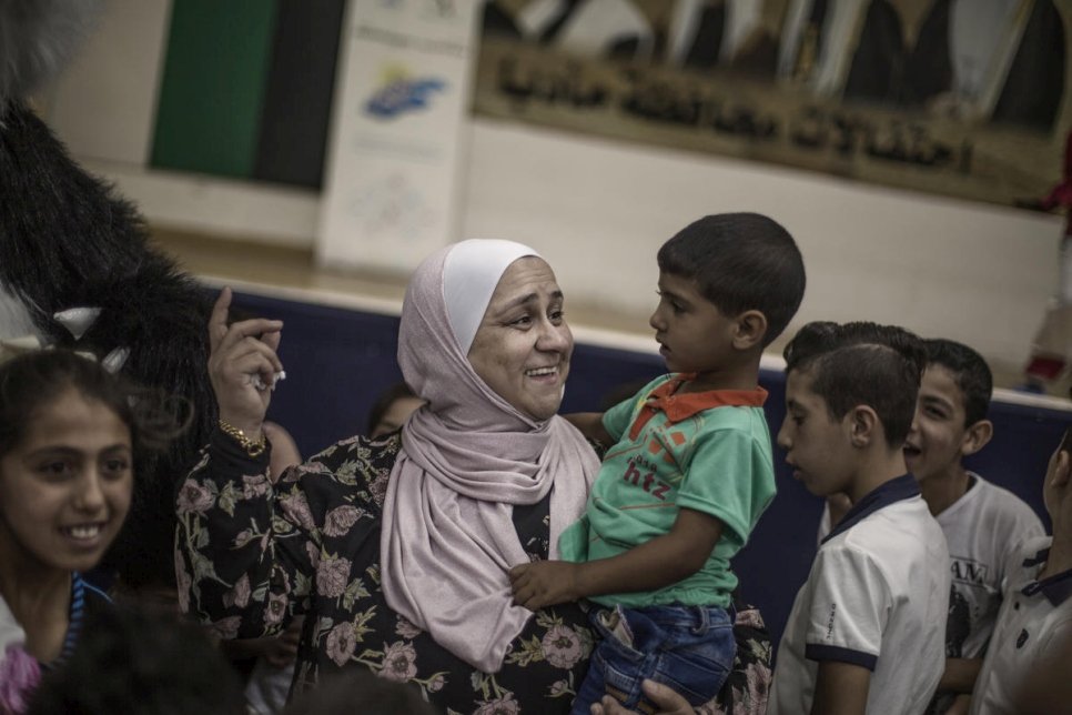 عبير خريشة تلاعب طفلاً سورياً لاجئاً في مركز مجتمعي في مأدبا، الأردن.