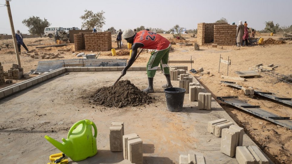 Des ouvriers du bâtiment représentant à la fois les communautés de réfugiés et d'accueil construisent la première des 1000 maisons en briques du village de Ouallam, à Tillaberi, dans le sud-ouest du Niger.