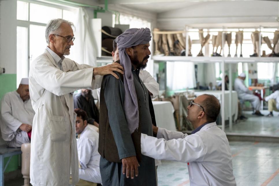 أخصائي العلاج الطبيعي ألبيرتو كايرو (يسار) يعالج مريضاً في مركزه في كابول.
