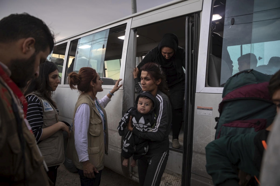 موظفو المفوضية والشركاء يساعدون اللاجئين السوريين الذين يصلون بالحافلة إلى مخيم بردرش في دهوك، العراق.