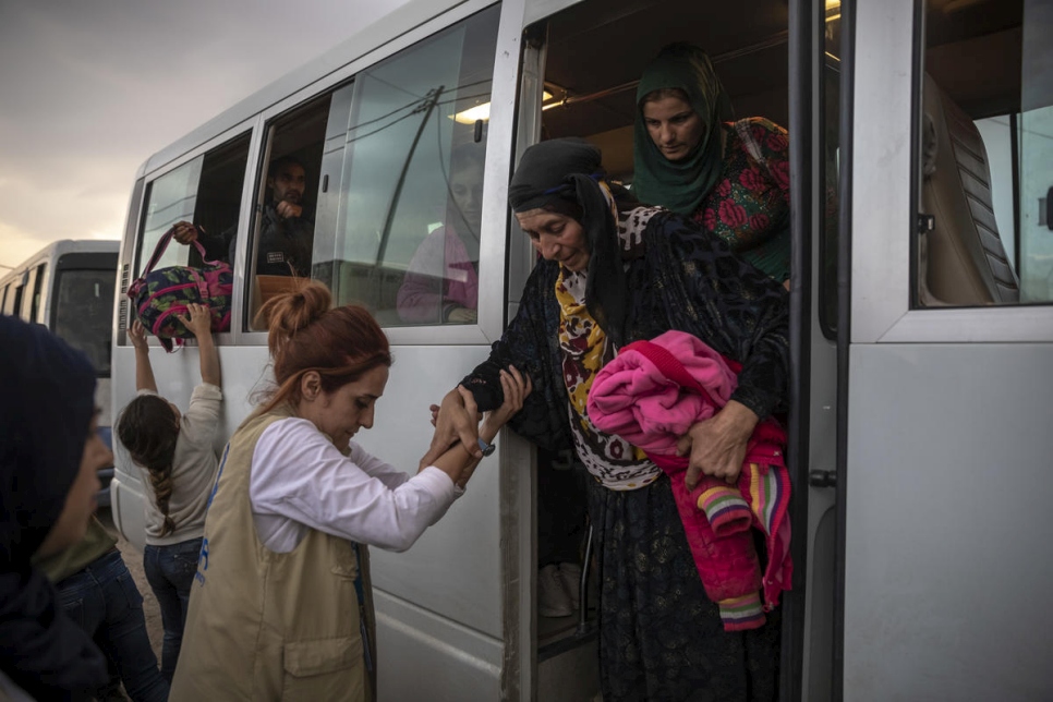 موظفو المفوضية والشركاء يساعدون اللاجئين السوريين الذين يصلون في حافلات إلى مخيم بردرش في دهوك، العراق.