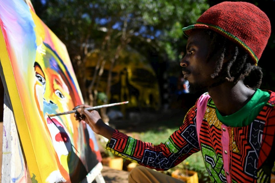 مايك، والذي فر من بوروندي في عام 2015، يعمل على لوحة في المركز الفني. 
