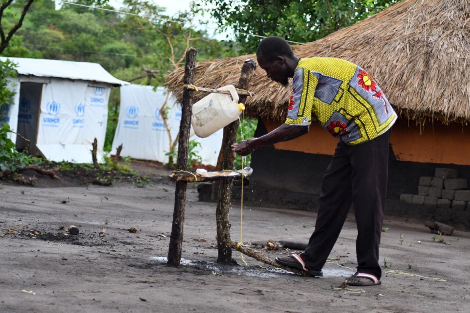 Chris, a South Sudanese refugee, uses a tippy tap he made using wood, an old jerry can and rope in Bele settlement, Democratic Republic of the Congo.