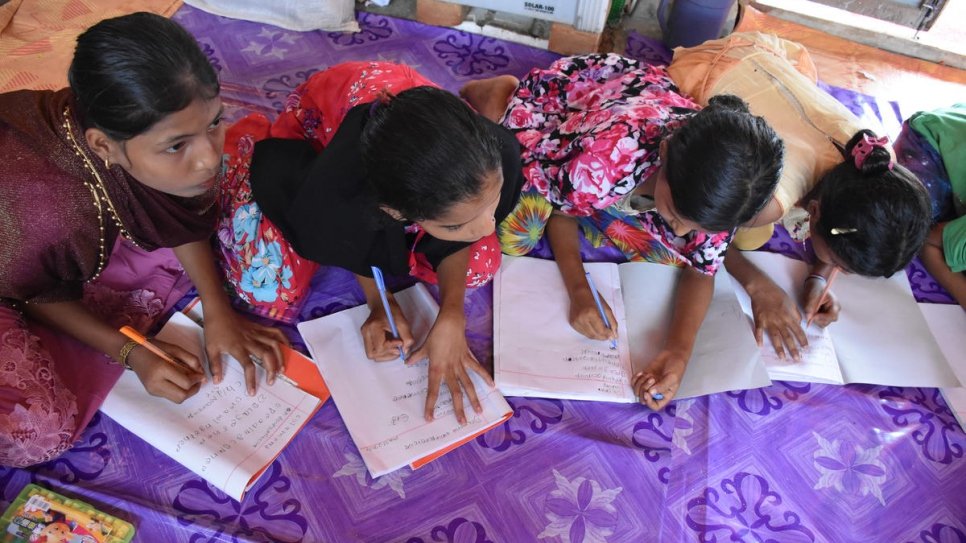 Des adolescentes recopient les résultats de leur exercice au Club Diamant pour adolescents géré par CODEC (Centre de développement communautaire), un partenaire du HCR. 