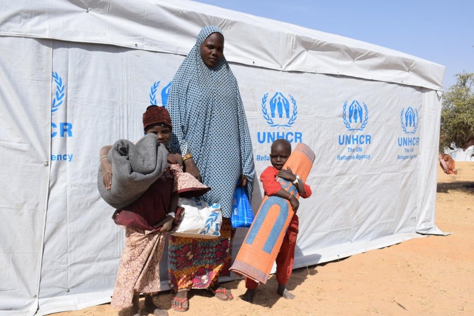 La réfugiée nigériane Aïcha Moussa et ses deux enfants devant leur nouvel abri au camp de Dar es-Salaam, au Tchad.