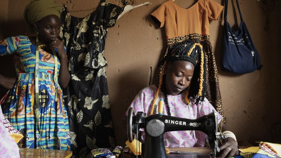 Marlyse Bangabou, 28 ans, fabrique une robe dans le centre de groupe des femmes debout, où elle apprend la couture.  