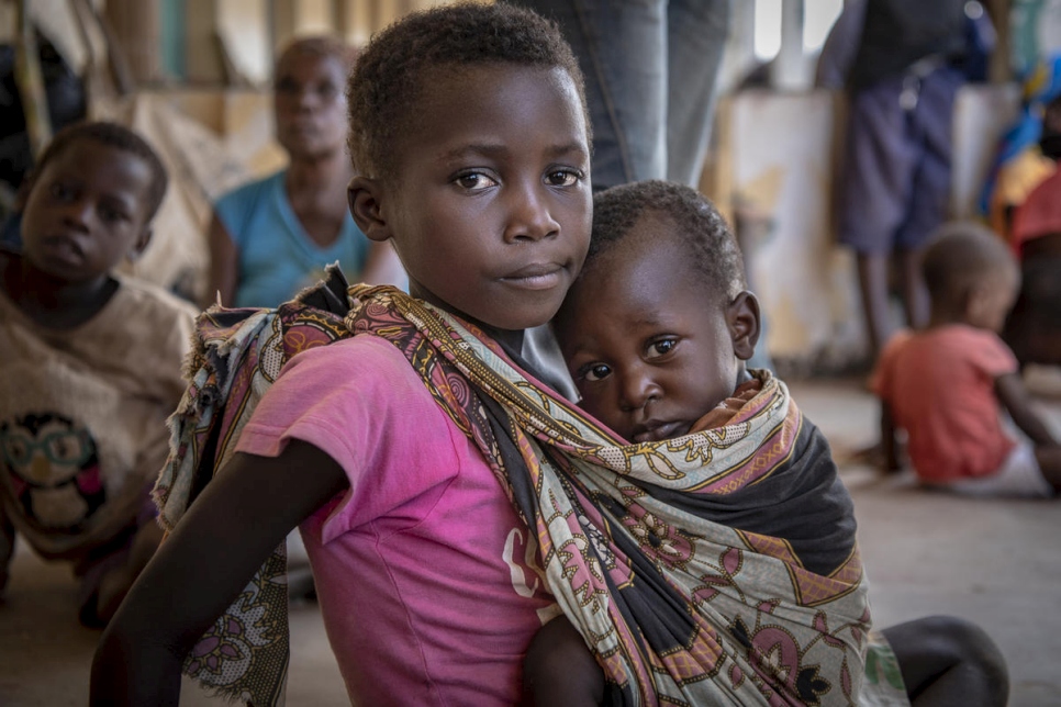 روزا البالغة من العمر سبع سنوات تحمل شقيقها الأصغر مانويل في مأوى للنساء والأطفال الذين شردهم إعصار إيداي في بوزي، موزمبيق.