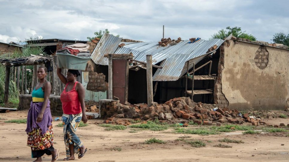 Deux femmes passent devant une maison qui s'est effondrée lorsque le cyclone Idai a frappé le camp de réfugiés de Tongogara, dans le district de Chipinge situé dans le sud-est du Zimbabwe. 