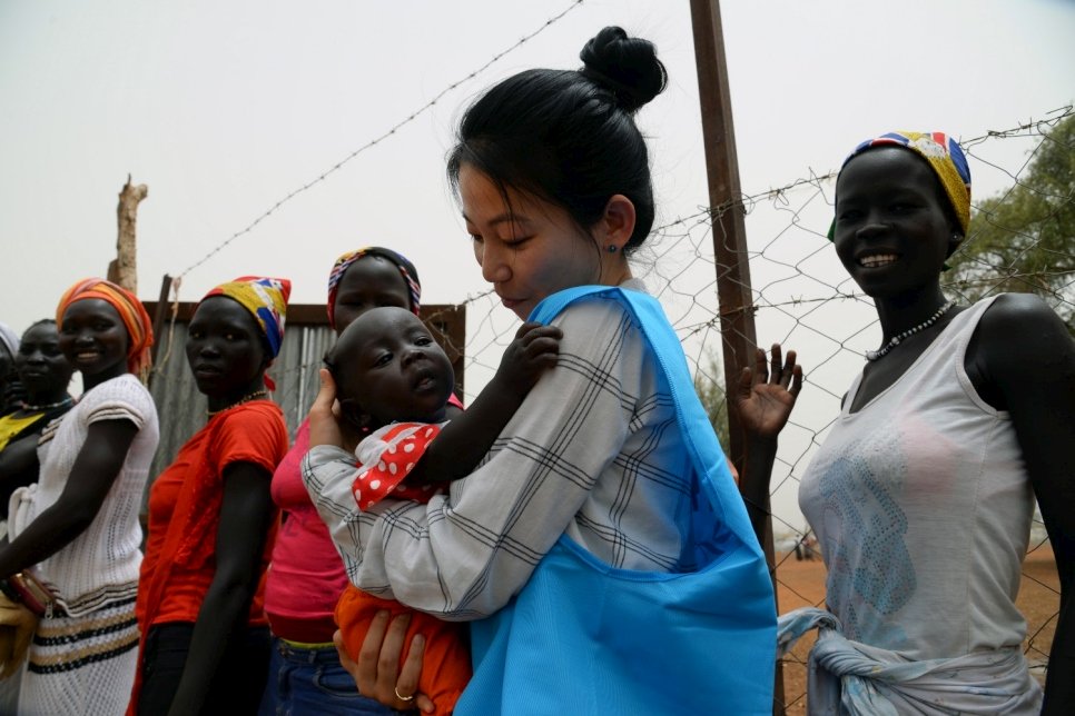 Eujin Byun, employée du HCR, tient un bébé réfugié dans les bras dans un camp de réfugiés au Soudan du Sud. 