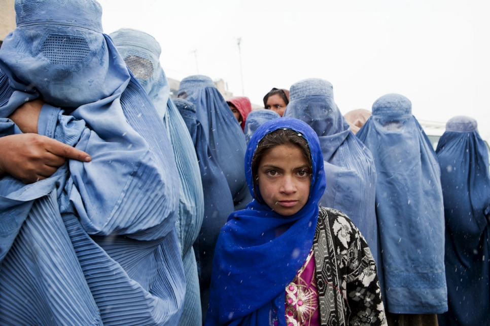 Une jeune fille fait la queue avec sa mère lors d'une distribution du HCR à Kaboul, en Afghanistan. 