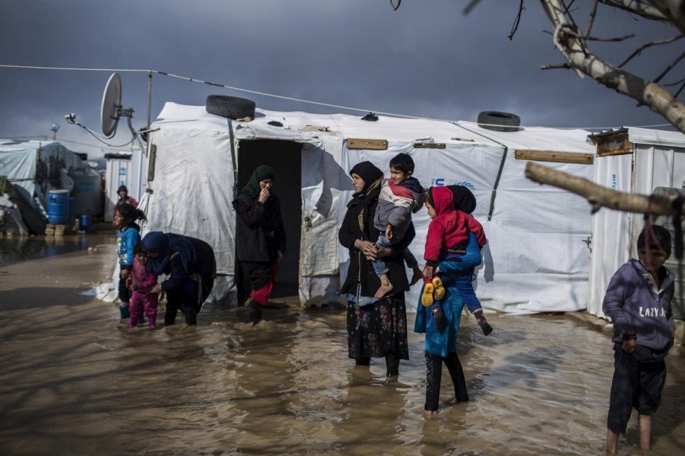 لاجئون سوريون يسيرون في شوارع غمرتها الفيضانات في مخيم الدلهمية العشوائي في سهل البقاع، لبنان، يناير 2019. 