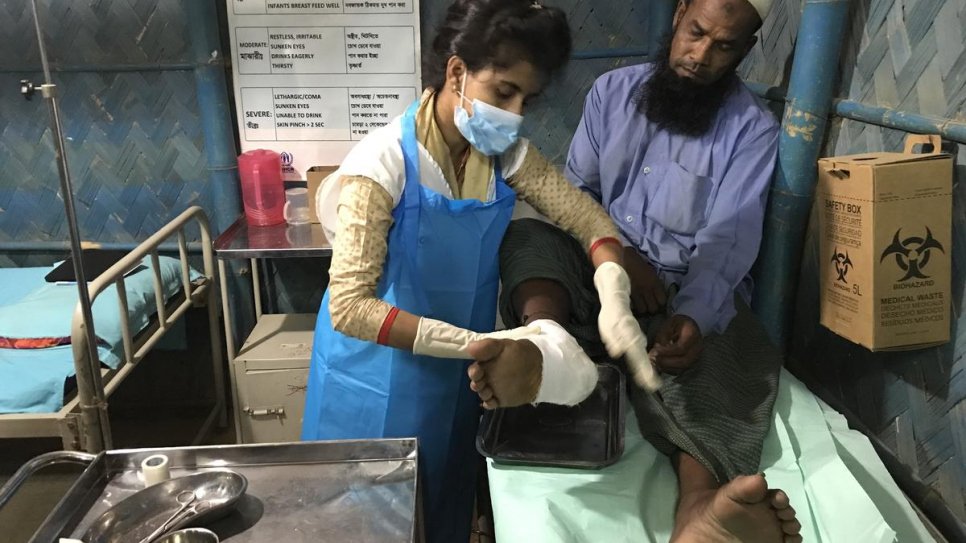 Sarmin Aktar Sathi, infirmière au dispensaire ouvert en continu de Kutupalong, en train de faire un bandage à Mohammad Sharif, un patient qui porte encore les cicatrices de la violence à laquelle il a échappé au Myanmar en 2017. 