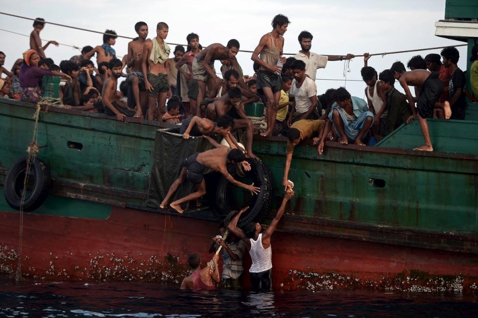 Plusieurs hommes rohingyas transfèrent des vivres, largués par un hélicoptère, à d'autres personnes à bord d'un bateau dérivant dans les eaux thaïlandaises en mer d'Andaman. Photo d'archives, 14 mai 2015. 
