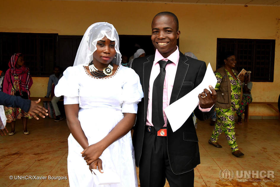 Two newly weds proudly holding their marriage certificate.
