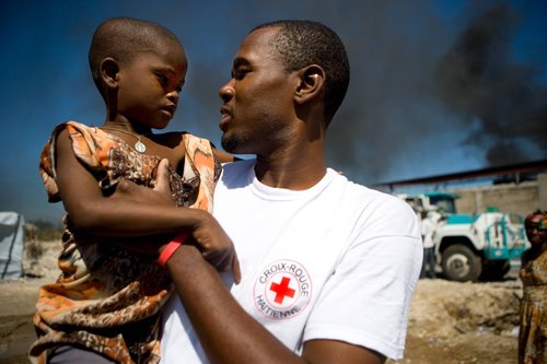 Humanitarian worker with refugee child on his arm