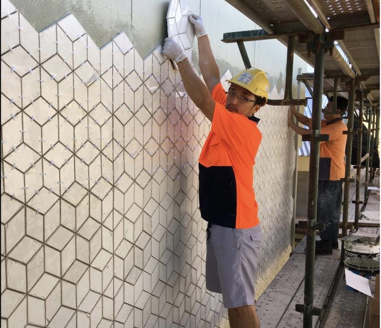 Man placing a tile in wall. 