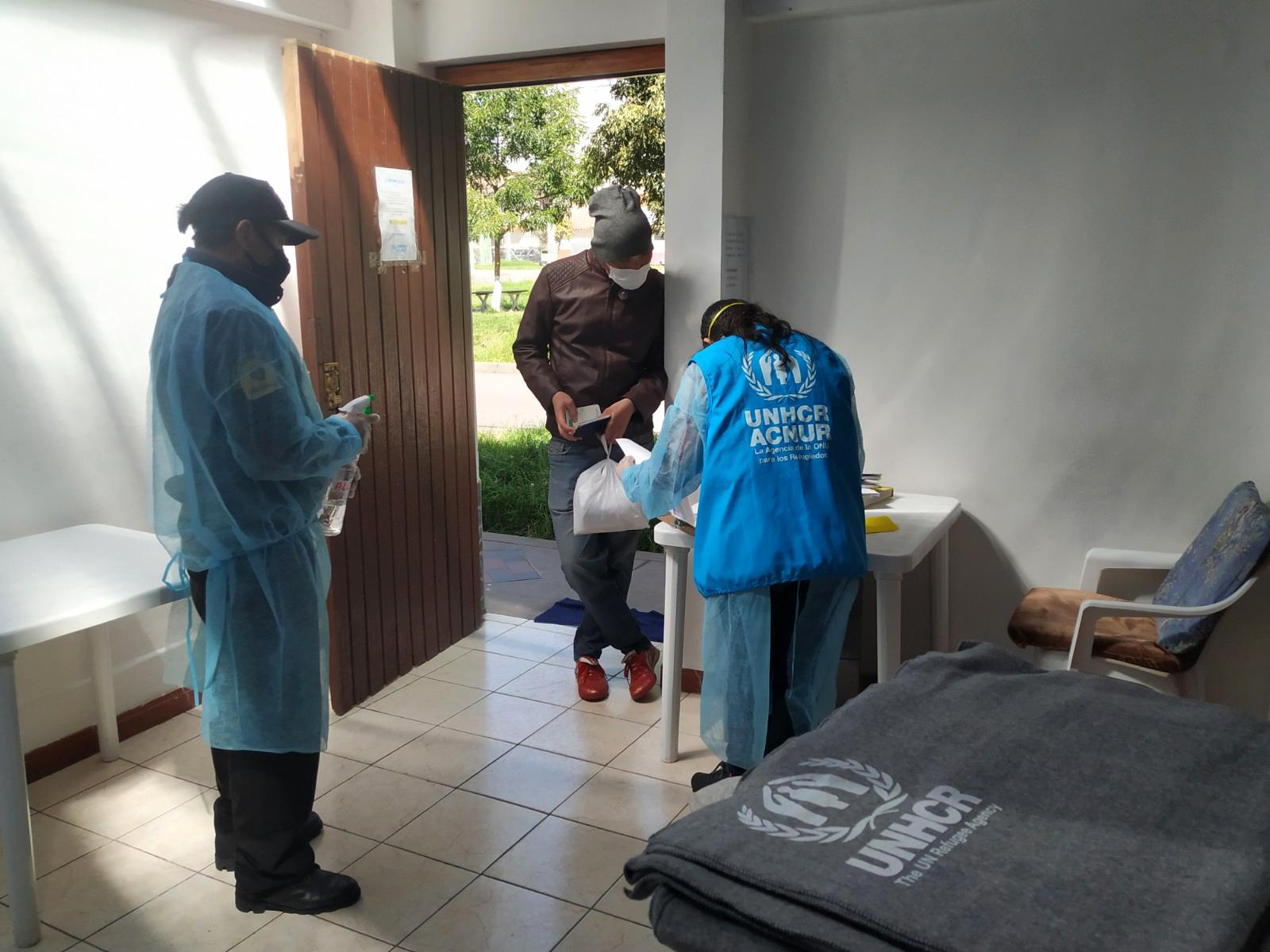 UNHCR staff distributing blankets to man.