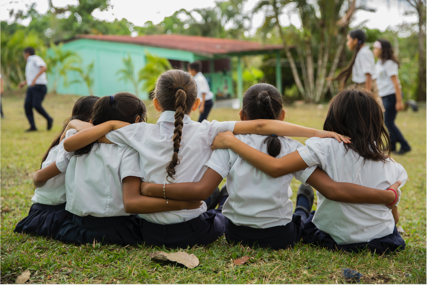 A group of girls sit with their backs to the camera, arm in arm.